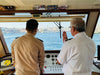 Image of a Captain ad a crew member talking in front the commands of a boat