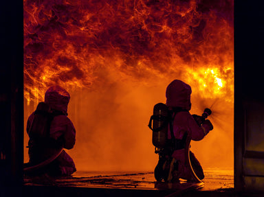 firemans kneeled down with their extinguisher and a real fire 